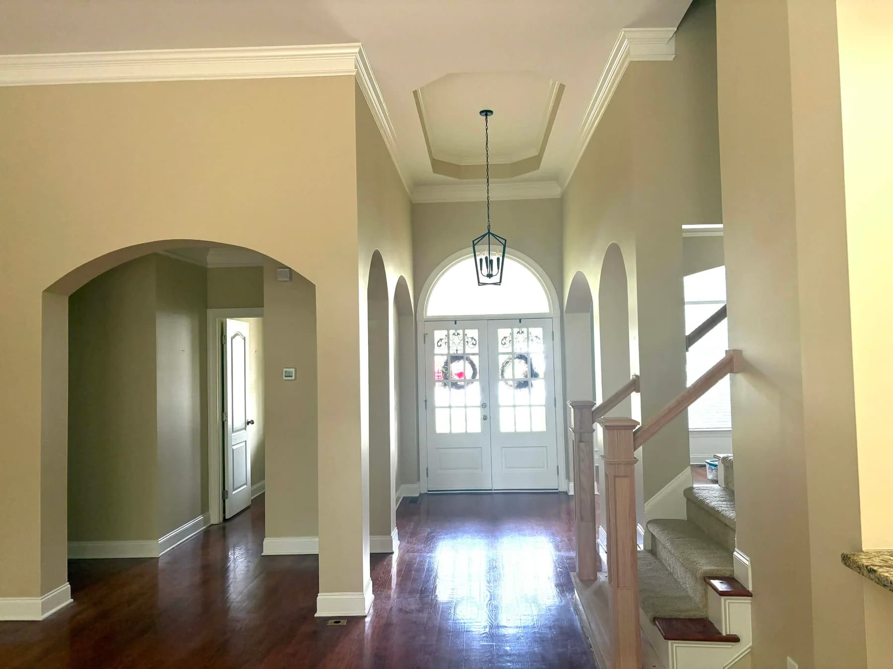 Finished foyer with smooth painted walls above the archways and white crown molding